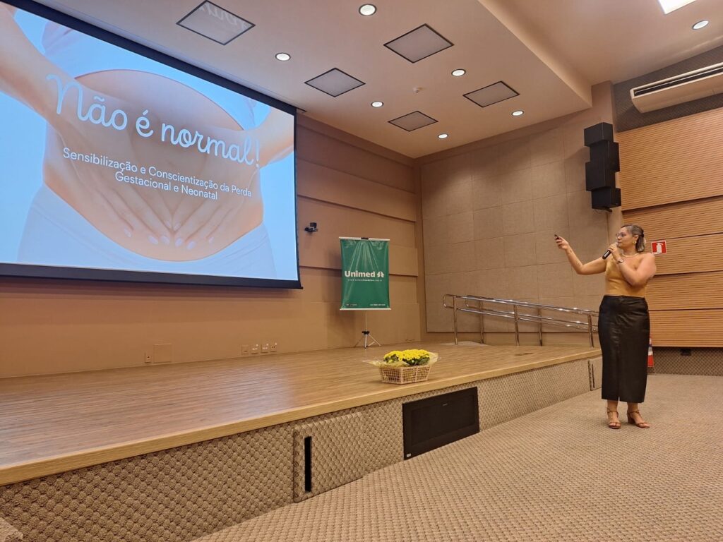 Palestrante apresenta uma formação sobre sensibilização para a perda gestacional e neonatal em auditório da Unimed.